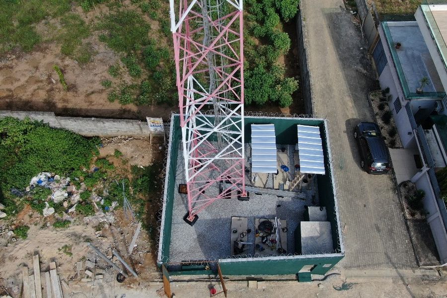Vue aérienne d'un site télécom avec pylône, clôture et équipements
